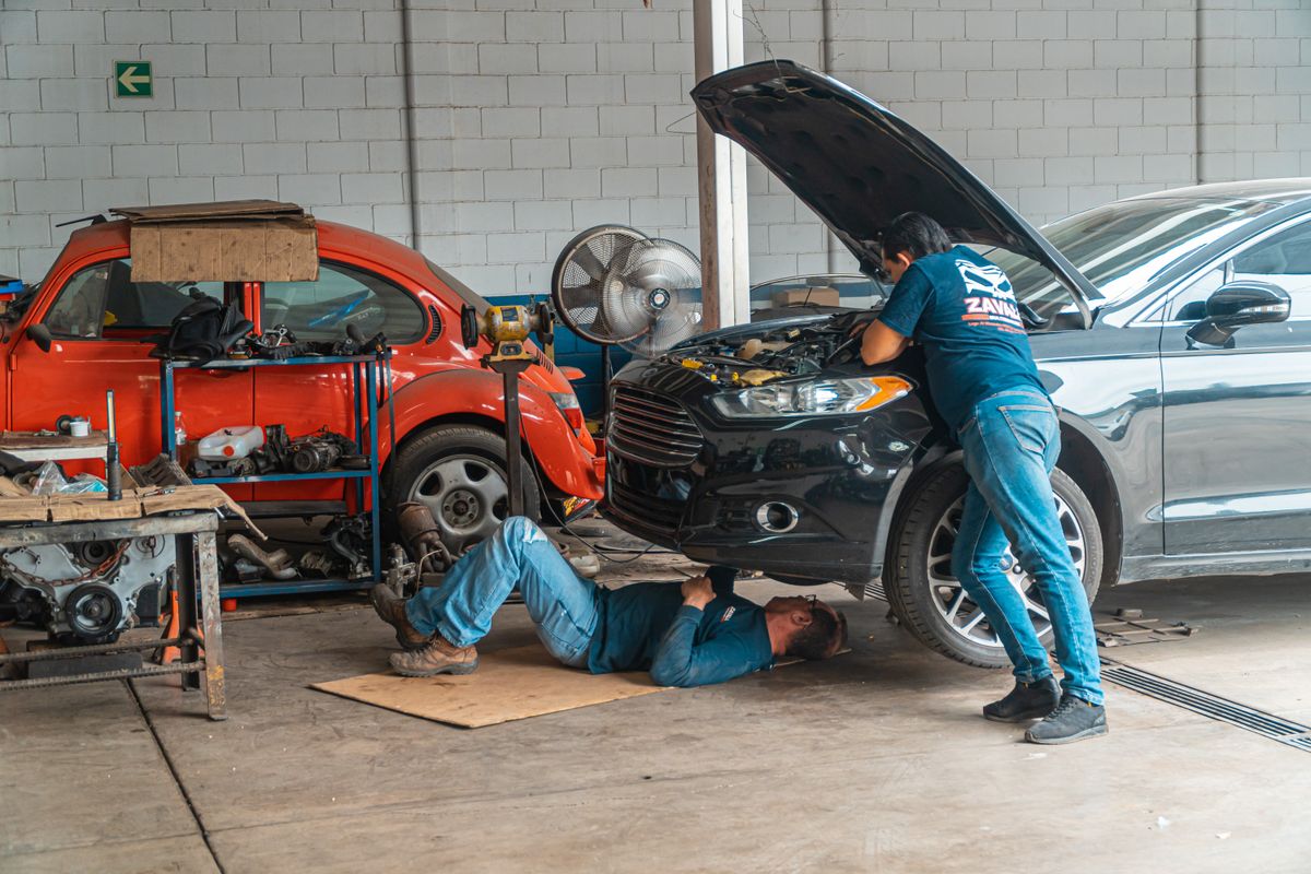 Dois mecânicos trabalhando juntos em um carro na oficina